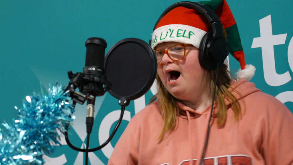 Woman with santa hat singing into professional microphone
